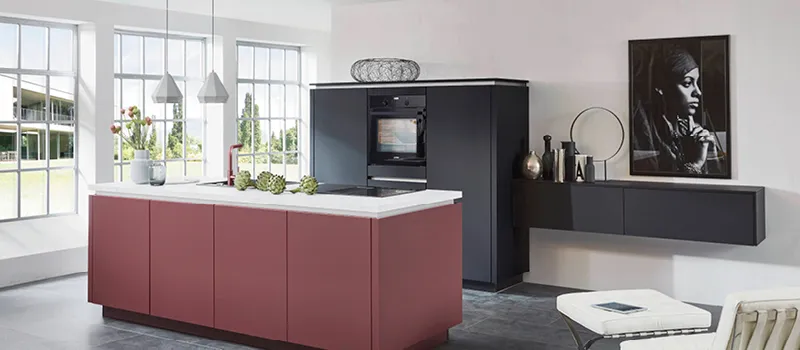 Moderne Designküche mit auffälliger roter Kochinsel, schwarzen Hochschränken, weißen Arbeitsplatten und großen Fenstern für ein lichtdurchflutetes, stilvolles Kocherlebnis.